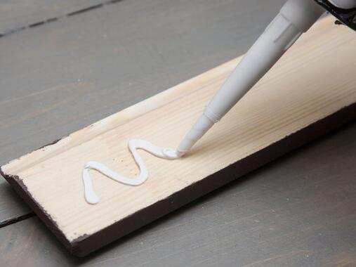 Applying grab adhesive in a zigzag pattern to a wooden board for strong bonding